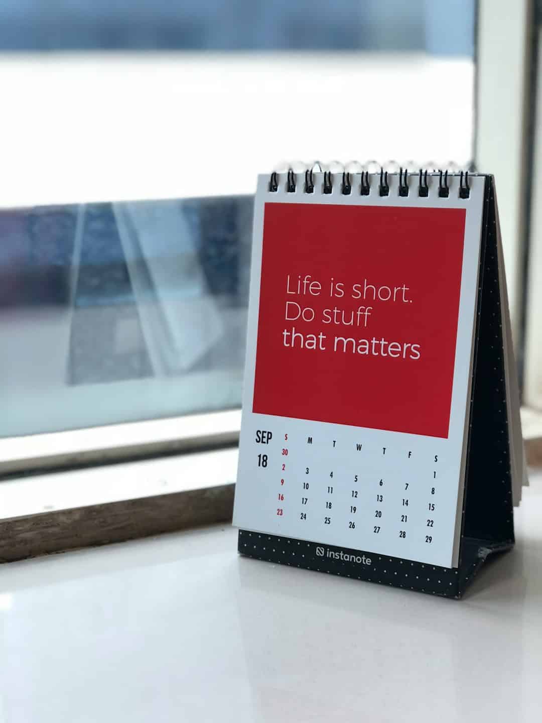 spiral freestanding calendar on white surface with the quote Life is short. Do stuff that matters" on a red background